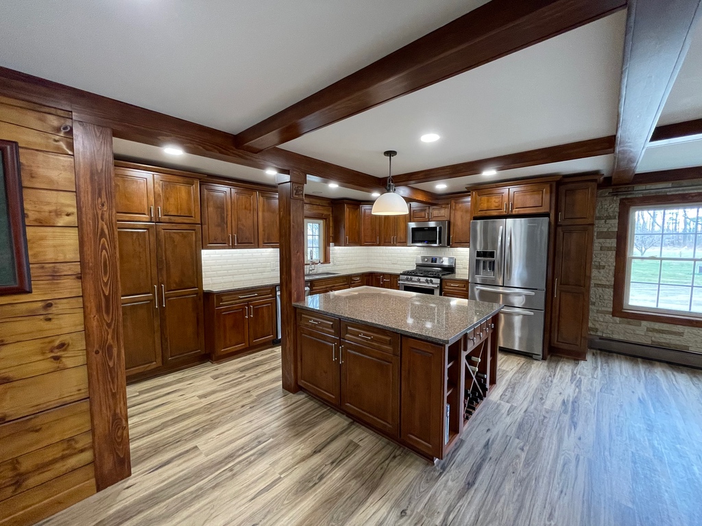 a completed kitchen remodel with a large island, wood floors and white subway tile backsplash
